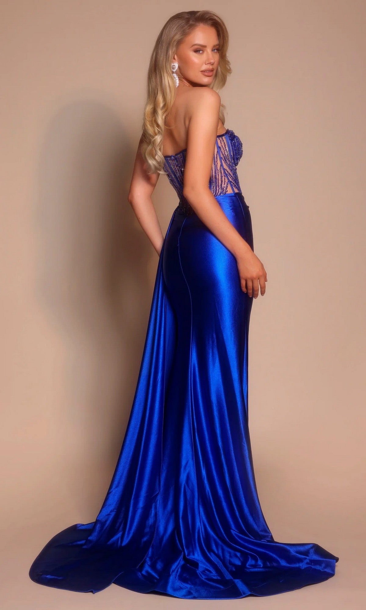 Woman wearing the Portia and Scarlett PS26056 long formal dress—a strapless, sweetheart neckline, fitted royal blue gown with a slight train—stands against a plain beige background.